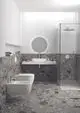Moderne Badezimmeransicht mit grauem Steinboden und Wandverkleidung. Sichtbare Designarmaturen und quadratischem Waschbecken, ausgestattet mit Ideal Standard-Produkten.